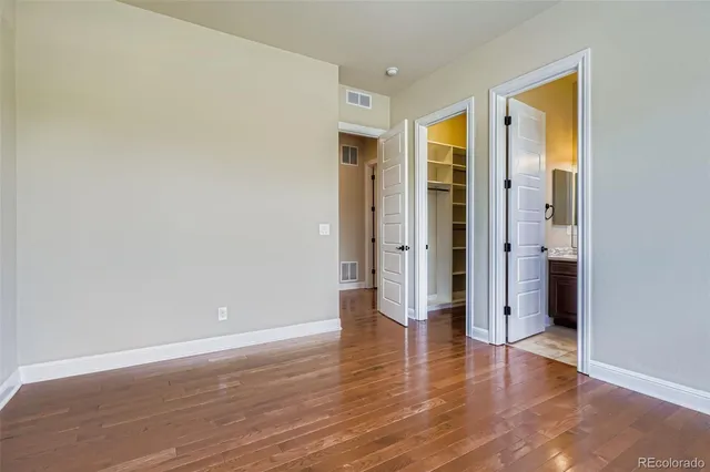 an empty room with wooden floor and a ceiling fan