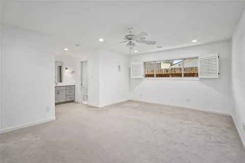 an empty room with windows and ceiling fan