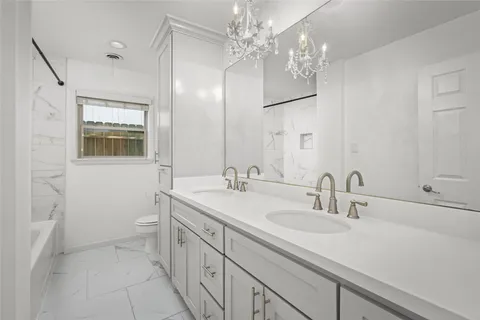 a bathroom with a double vanity sink mirror and toilet