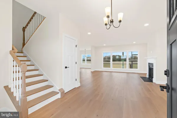 a view of an empty room with wooden floor and stairs