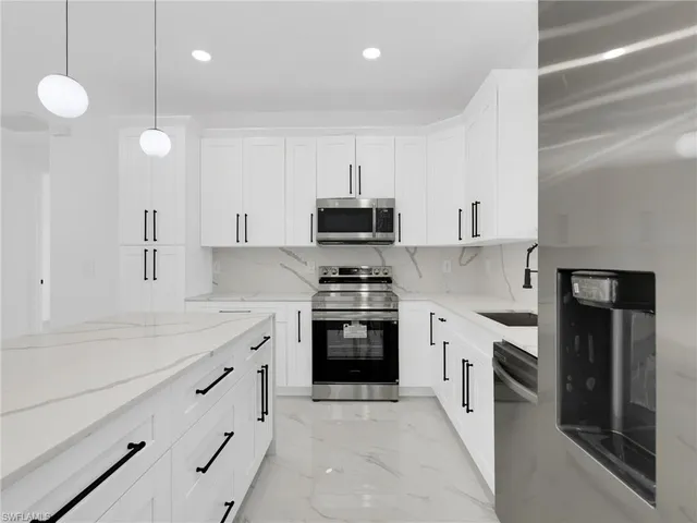 a kitchen with kitchen island white cabinets and refrigerator