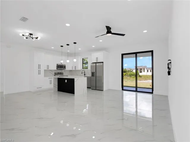 a large white kitchen with a sink stainless steel appliances and cabinets