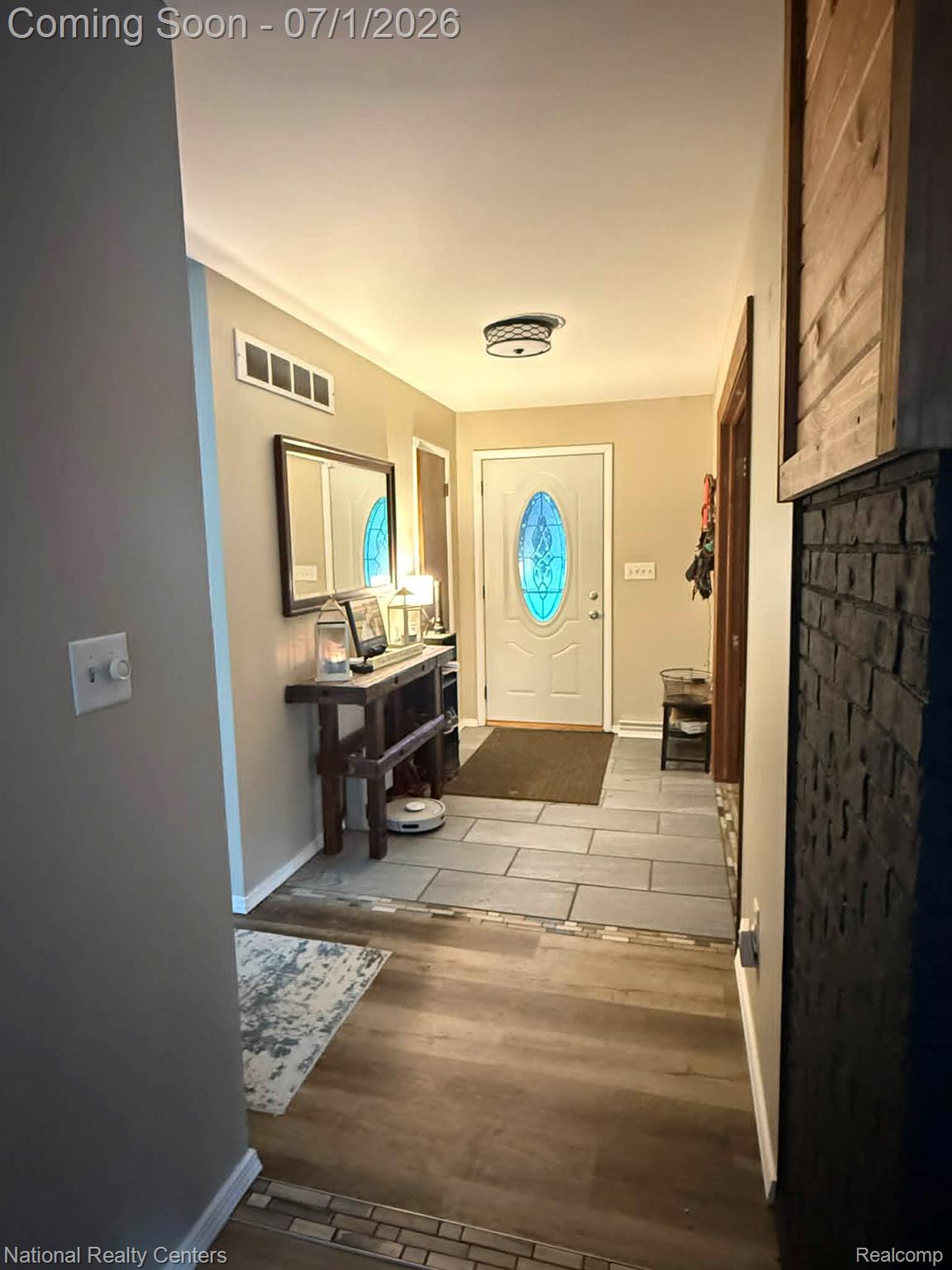 1330 Brauer Road Oxford, MI 48371 - Photo 38 of 54 Entryway featuring a decorative glass panel front door, wood-finish flooring, and a mixed-material accent wall with brick-style detailing