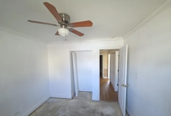 an empty room with closet and a ceiling fan