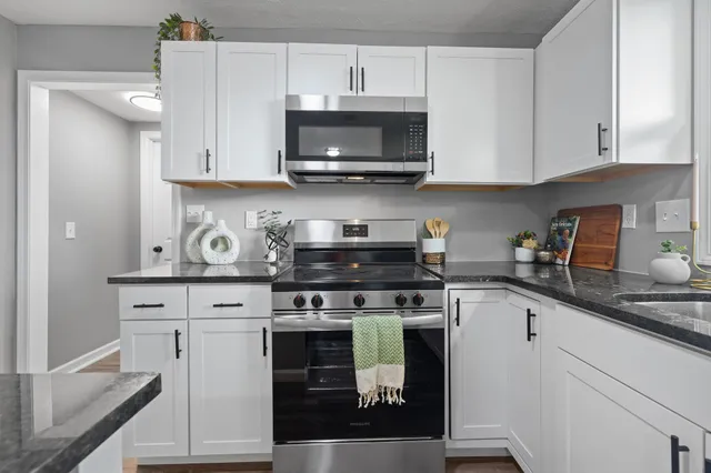 a kitchen with stainless steel appliances granite countertop a stove a sink and a microwave