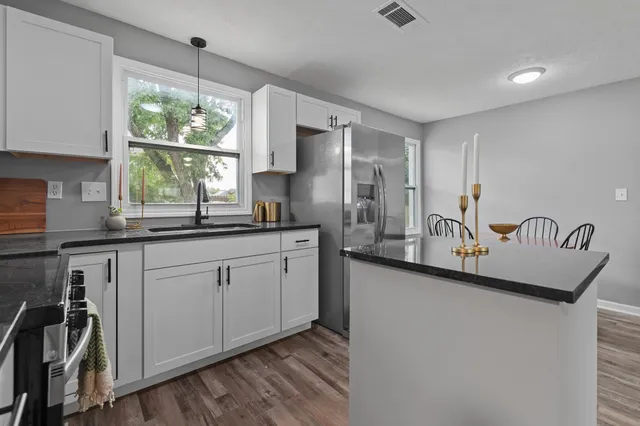 a kitchen with stainless steel appliances granite countertop a sink a stove and a refrigerator