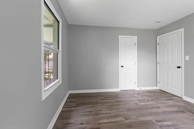 a view of an empty room with wooden floor and window