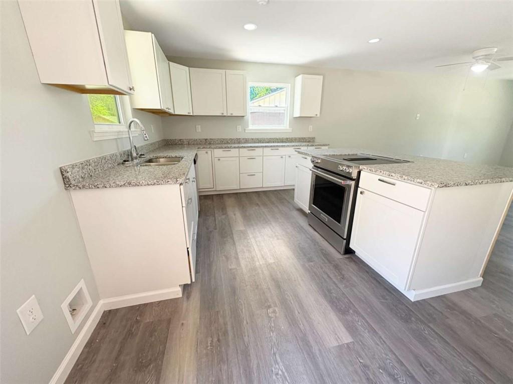 24 George Street Forsyth, GA 31029 - Photo 11 of 17 a kitchen with granite countertop wooden floors and white stainless steel appliances