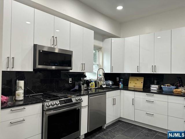 194 Washington Avenue, Unit 1 Rutherford, NJ 07070 - Photo 19 of 29 a kitchen with white cabinets and black appliances