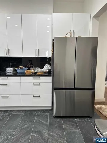 a view of kitchen with granite countertop white cabinets