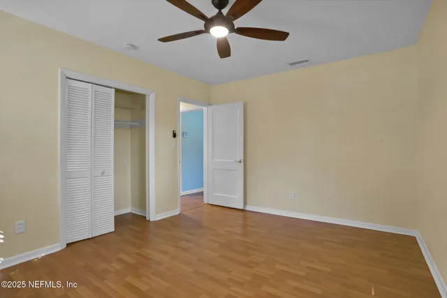 an empty room with a window and a ceiling fan