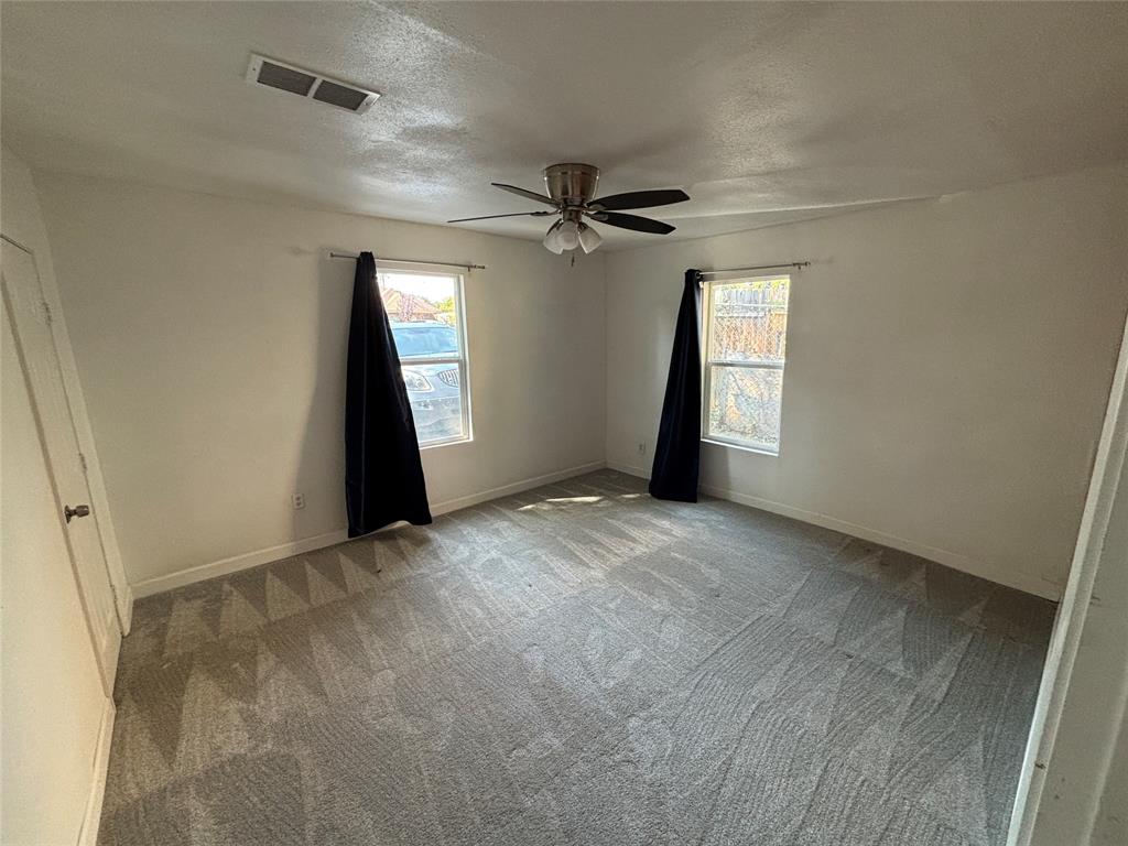 1303 East Myrtle Street, Unit A Fort Worth, TX 76104 - Photo 7 of 9 an empty room with windows and fan
