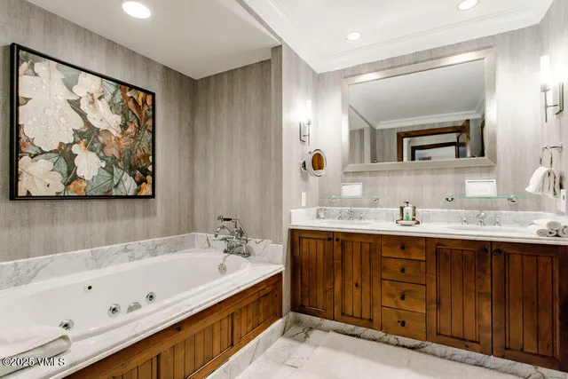 a bathroom with a tub a sink and mirror