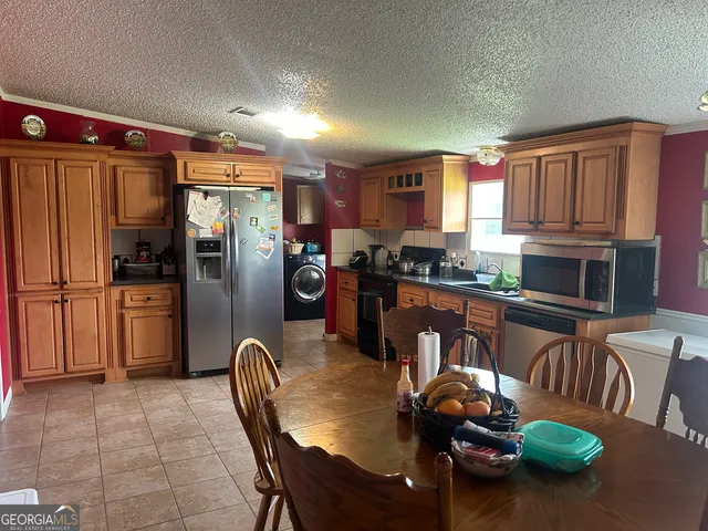 a kitchen with stainless steel appliances granite countertop a refrigerator a stove a sink dishwasher a dining table and chairs with wooden floor