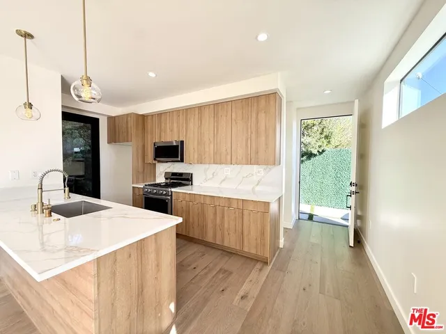 a kitchen with granite countertop a sink a counter space appliances and cabinets