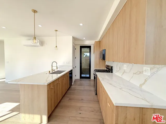 a large kitchen with kitchen island a sink a counter space and stainless steel appliances