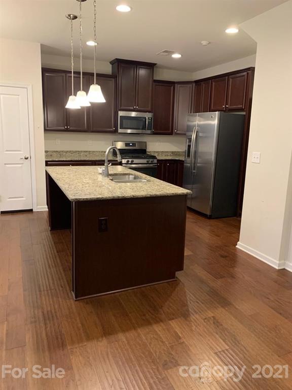 733 Dynamo Street Northwest Concord, NC 28027 - Photo 7 of 24 a kitchen with stainless steel appliances granite countertop a refrigerator a stove a sink and a microwave