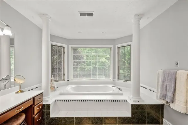 a spacious bathroom with a granite countertop sink and a bathtub