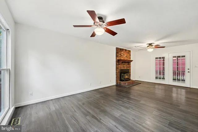 an empty room with wooden floor chandelier fan and windows
