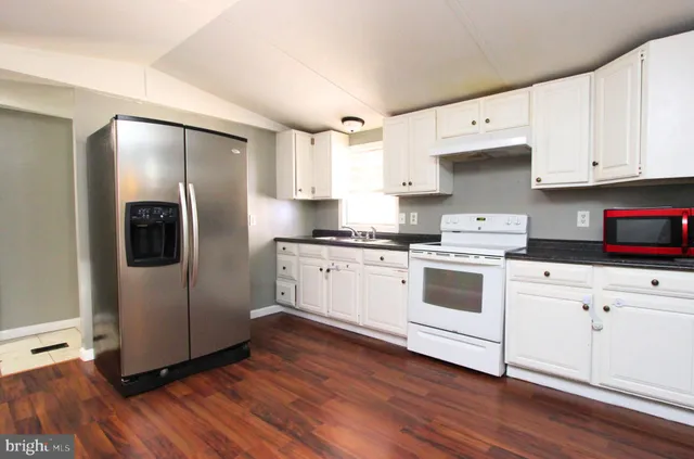 a kitchen with granite countertop white cabinets and white appliances