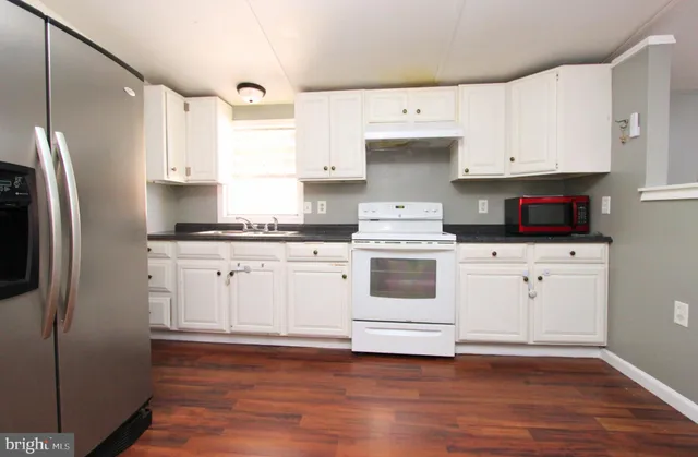 a kitchen with granite countertop white cabinets and white appliances