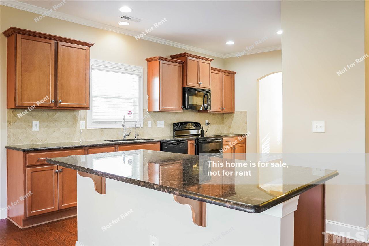 7549 Channery Way Raleigh, NC 27616 - Photo 4 of 27 a kitchen with kitchen island granite countertop a sink stove and cabinets