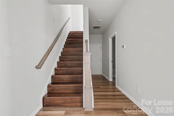 a view of an empty room with wooden floor and closet