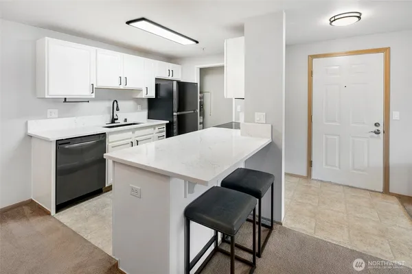 a kitchen with stainless steel appliances a stove a sink refrigerator and white cabinets