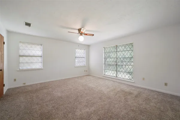 an empty room with windows and fan