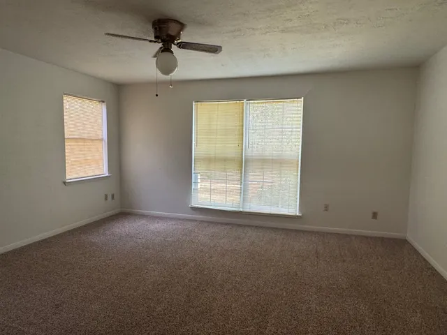 an empty room with windows and ceiling fan