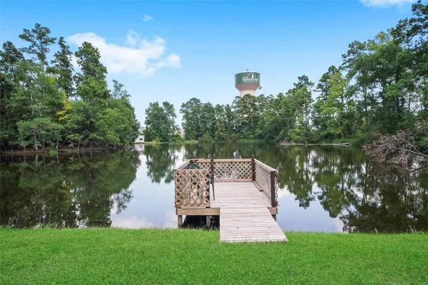 a view of a lake with a big yard and large trees