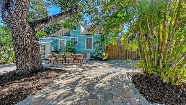 a backyard of a house with table and chairs under an umbrella