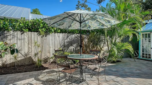 a view of a backyard with table and chairs potted plants and a large tree