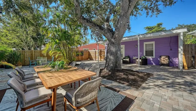 a view of a backyard with table and chairs and a large tree
