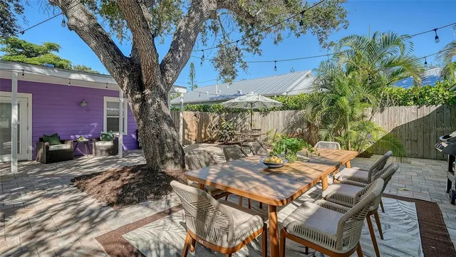 a view of a patio with table and chairs potted plants and a large tree