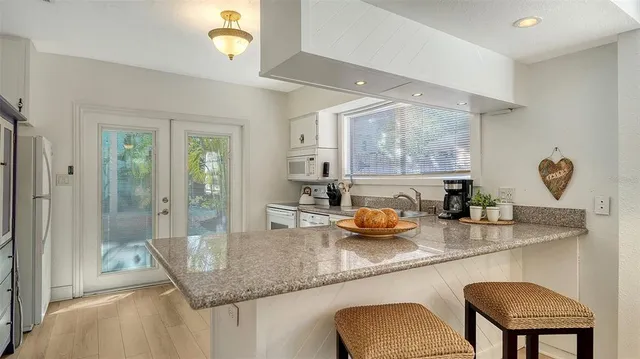 a kitchen with kitchen island granite countertop a sink cabinets and wooden floor