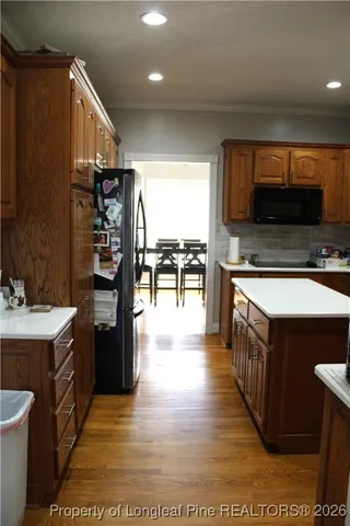 a open kitchen with stainless steel appliances kitchen island granite countertop a stove top oven a sink dishwasher and a dining table with wooden floor