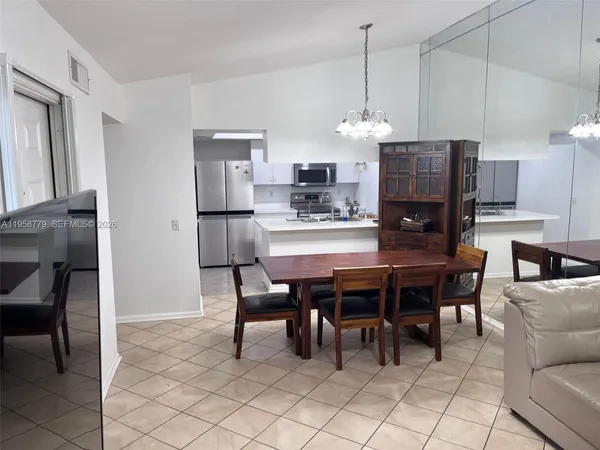 a dining table chairs and a refrigerator in a kitchen