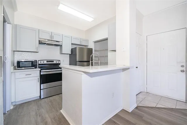 a kitchen with cabinets stainless steel appliances and wooden floor