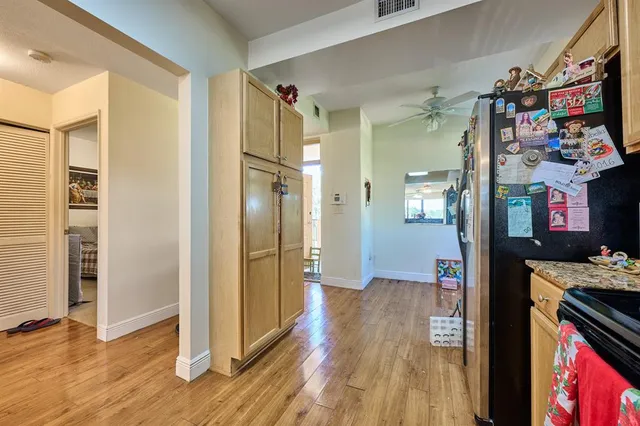 a view of a hallway with wooden floor and a kitchen