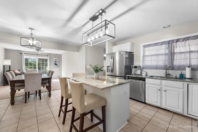 a kitchen with stainless steel appliances granite countertop a sink a stove a dining table and chairs with wooden floor