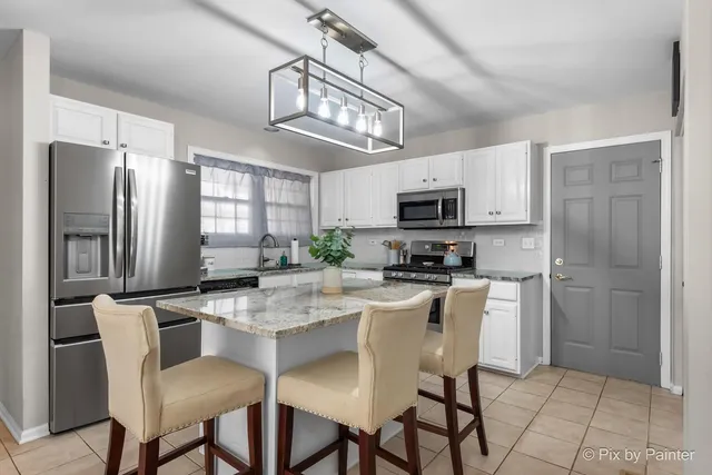 a kitchen with stainless steel appliances granite countertop a refrigerator a stove a microwave oven a sink dishwasher and a refrigerator with wooden floor