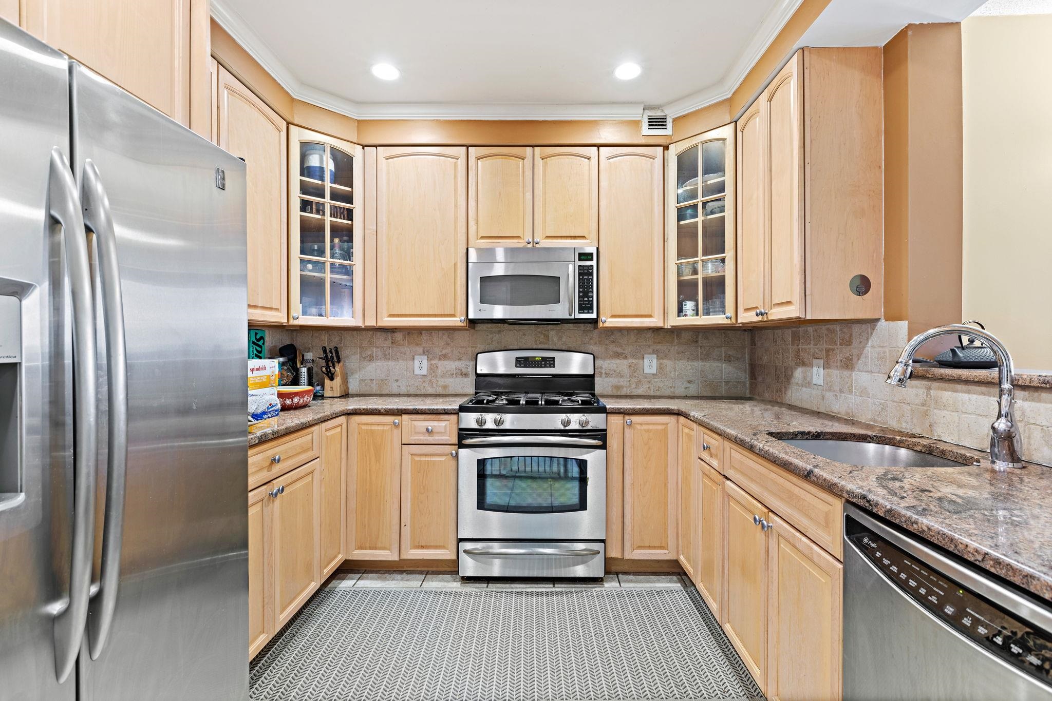 311 Washington Street, Unit 9C Jersey City, NJ 07302 - Photo 5 of 17 a kitchen with stainless steel appliances granite countertop a stove a sink and a refrigerator