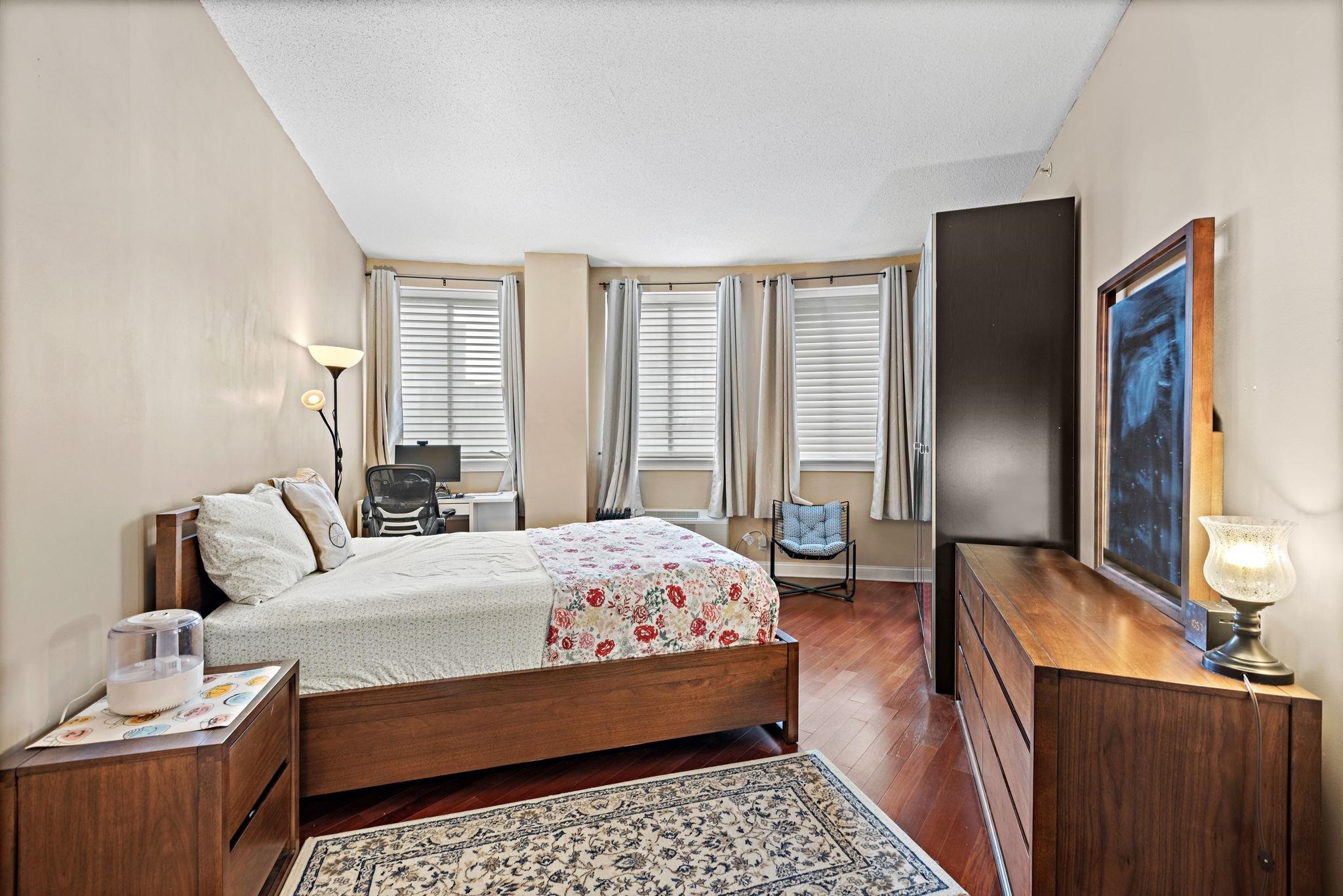 311 Washington Street, Unit 9C Jersey City, NJ 07302 - Photo 10 of 17 a bedroom with a bed and wooden floor
