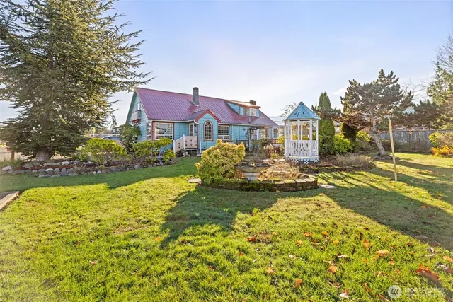 a view of a house with a yard and a large tree
