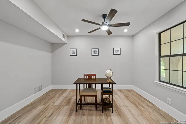 a view of a workspace room with wooden floor and a window