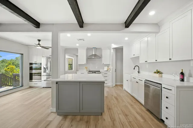 a kitchen with stainless steel appliances a sink dishwasher stove refrigerator and cabinets with wooden floor