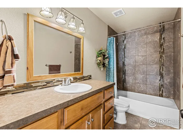 a bathroom with a granite countertop sink toilet a mirror a vanity and bathtub