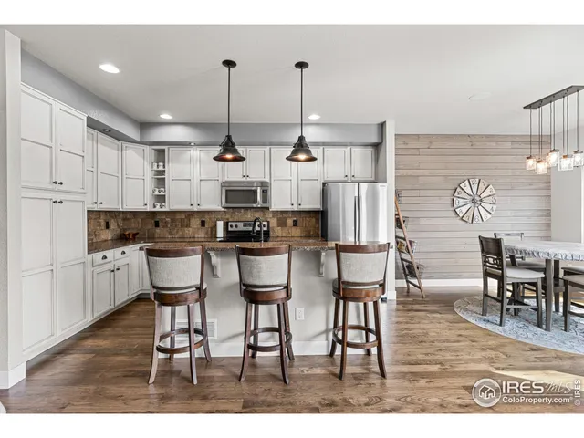 a kitchen with stainless steel appliances kitchen island granite countertop a table chairs stove and white cabinets