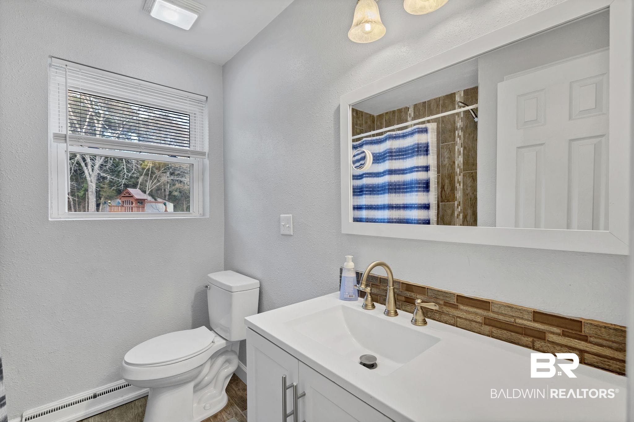 4690 Lott Road Eight Mile, AL 36613 - Photo 27 of 45 Bathroom featuring vanity, a baseboard radiator, toilet, and a shower with shower curtain